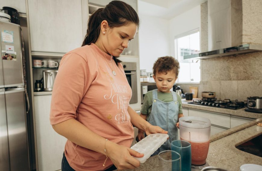 A woman and her son making a drink together in a modern kitchen.