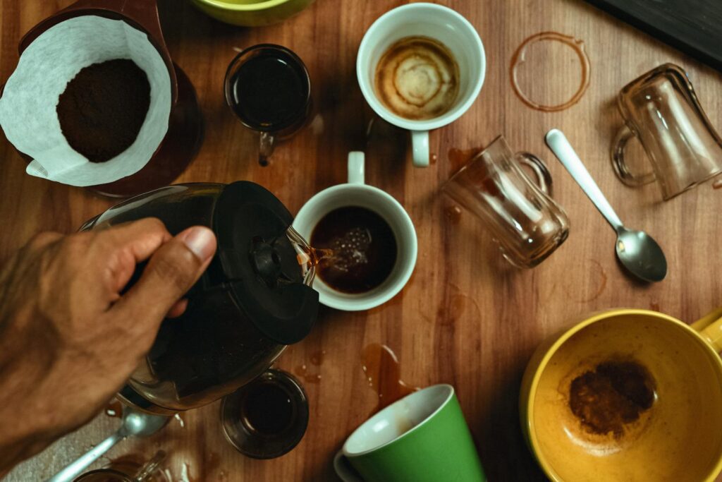 Dynamic overhead photo of coffee being poured into mugs with spills and stained cups.