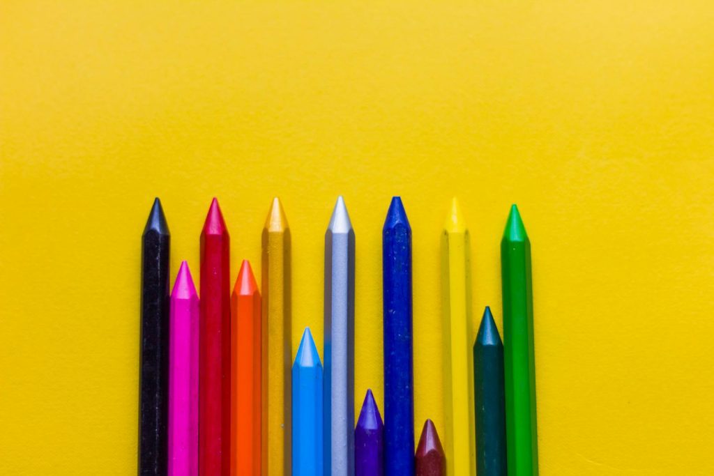 Close-up of colorful crayons arranged on a bright yellow background, perfect for creative and educational themes.