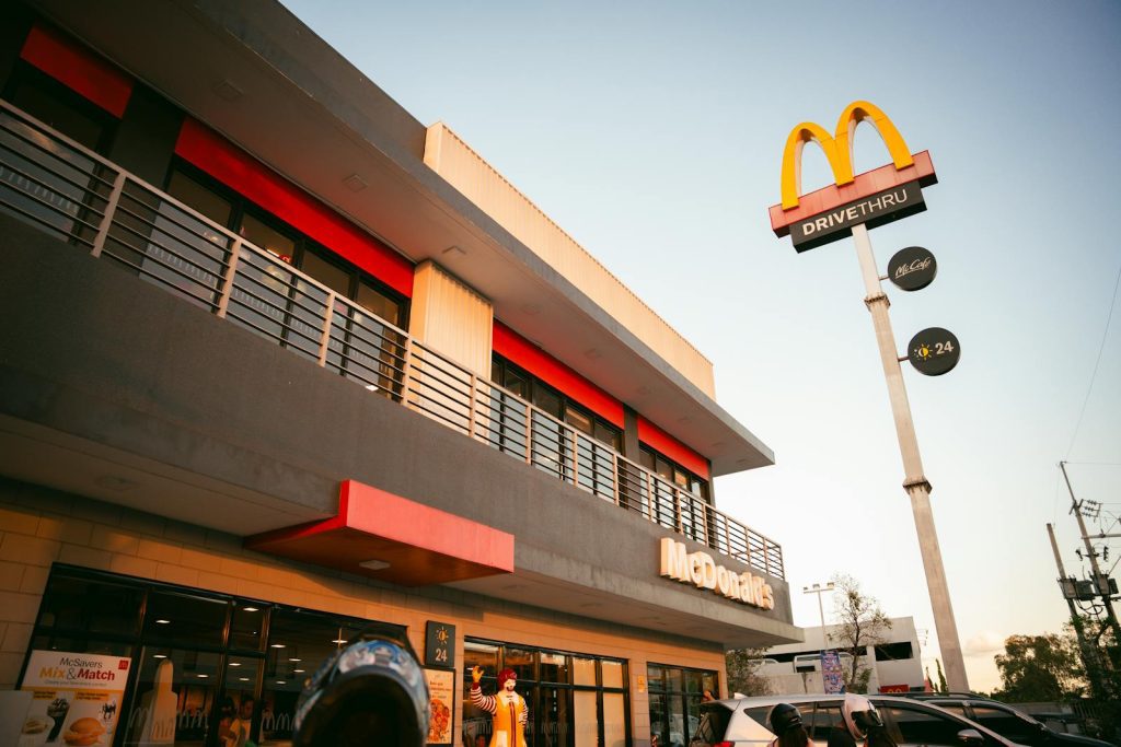 A modern McDonald's fast food restaurant with distinctive branding and drive-thru facilities under a clear blue sky.