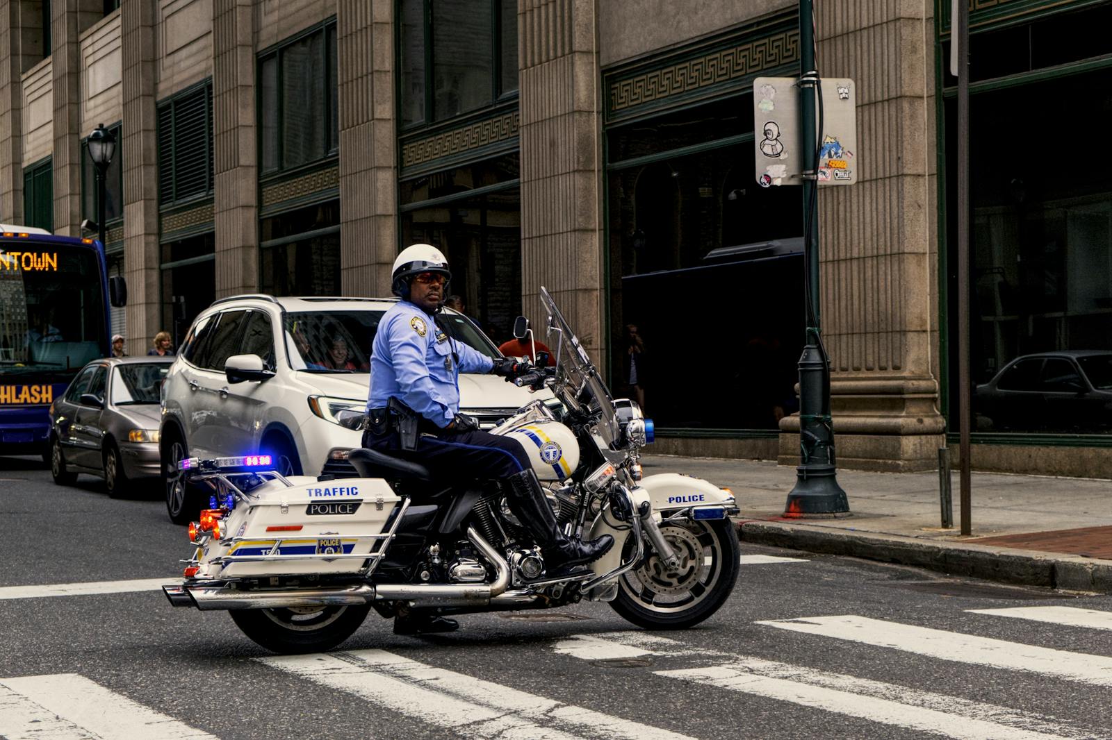 Traffic police officer riding a motorcycle in a busy city intersection.