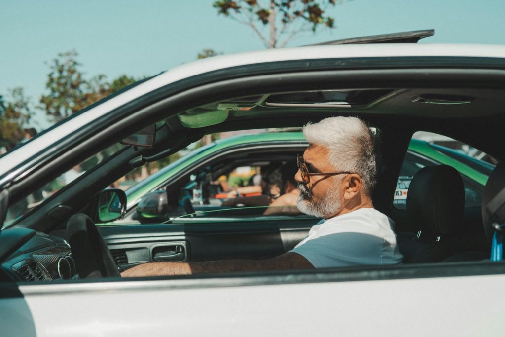Senior man driving a vintage sports car on a sunny day in İstanbul, Türkiye.