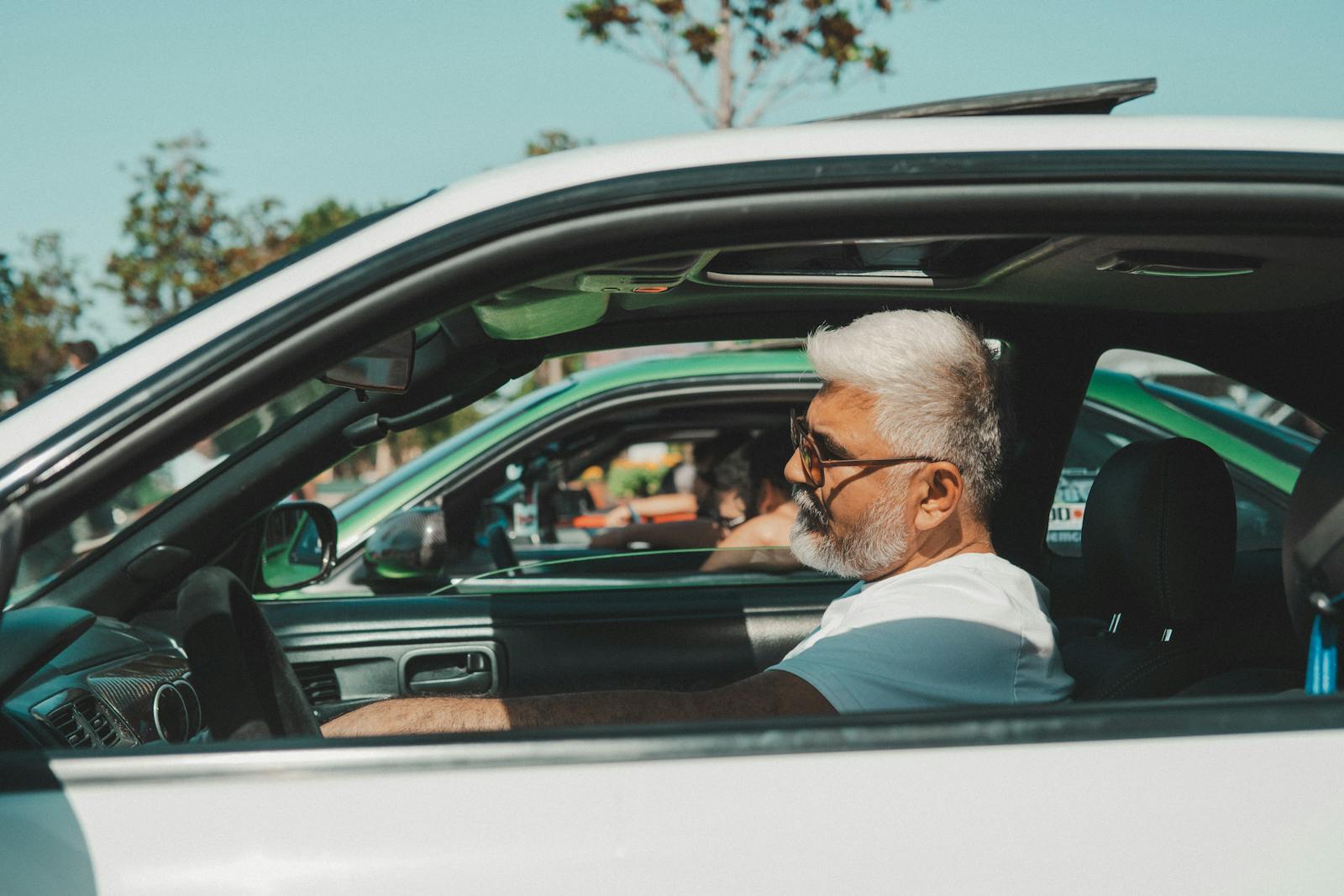 Senior man driving a vintage sports car on a sunny day in İstanbul, Türkiye.