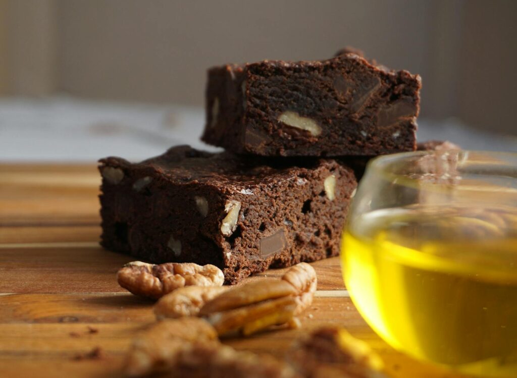 Close-up of chocolate brownies with nuts beside a cup of tea on a wooden table.