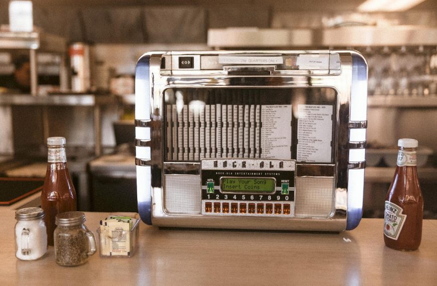 Vintage jukebox with condiments on a wooden counter in a cozy diner interior.
