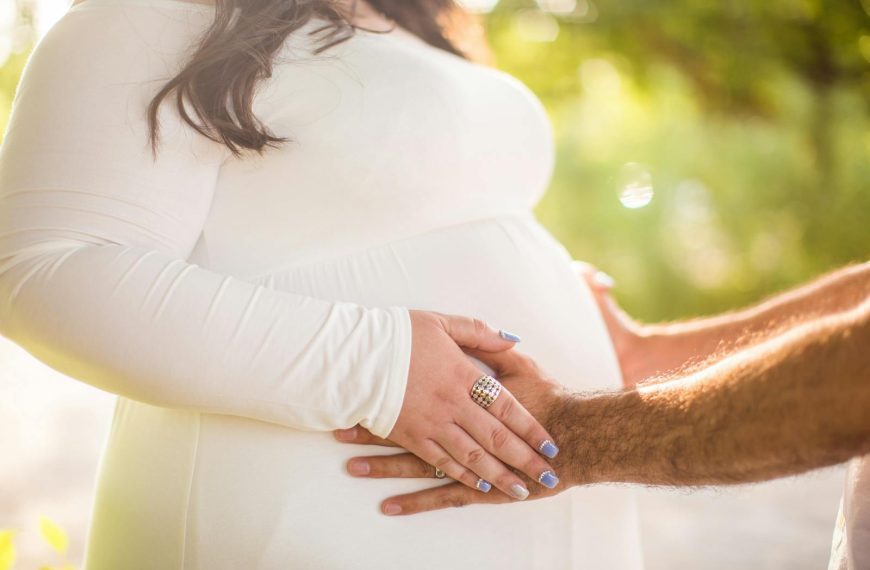 A tender moment showcasing an expectant couple's embrace outdoors.
