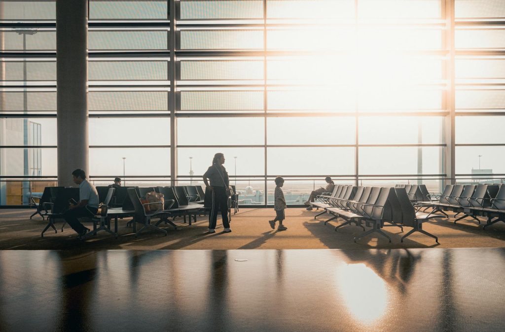 Silhouettes of travelers in a sunlit airport terminal in Shanghai, China.