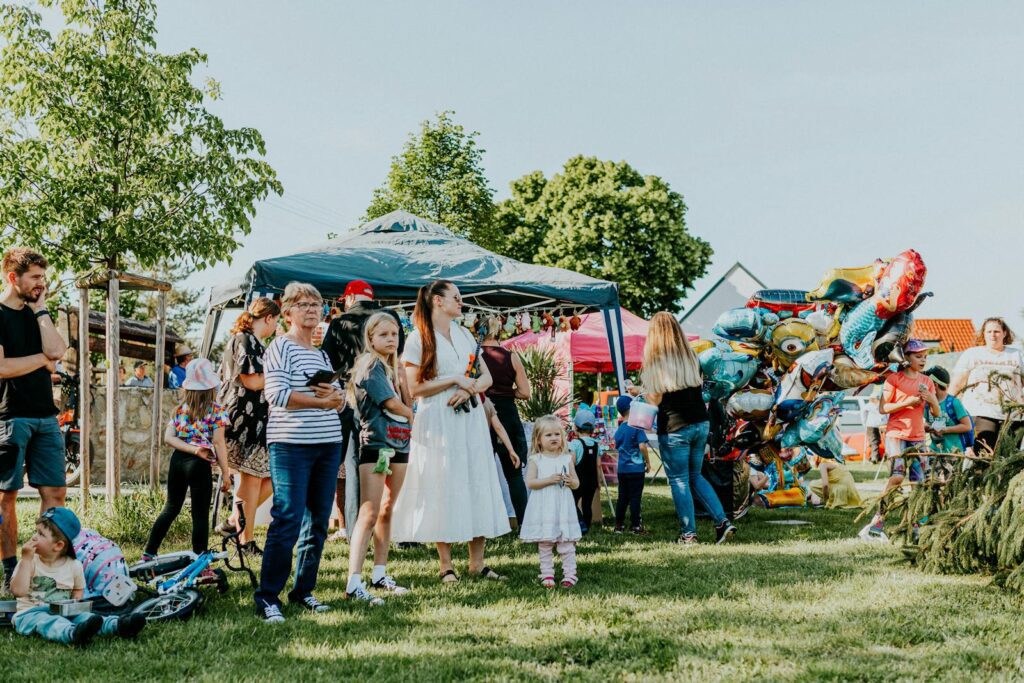 A lively outdoor gathering with families enjoying balloons and a sunny day.