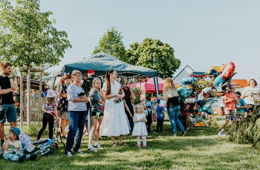 A lively outdoor gathering with families enjoying balloons and a sunny day.