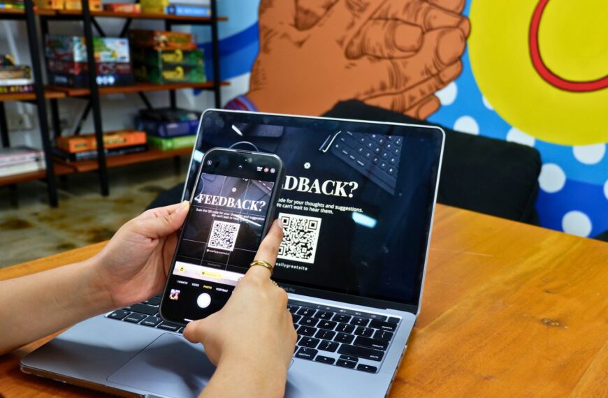 a person using a cell phone while sitting in front of a laptop