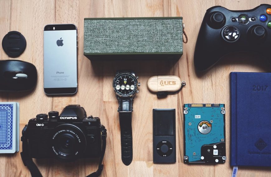 Flat lay of various modern gadgets, accessories, and tech items on wooden surface.