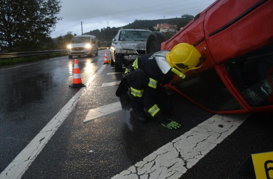 Firefighter attending to an overturned car on a rainy road in Póvoa de Lanhoso, Braga, Portugal.