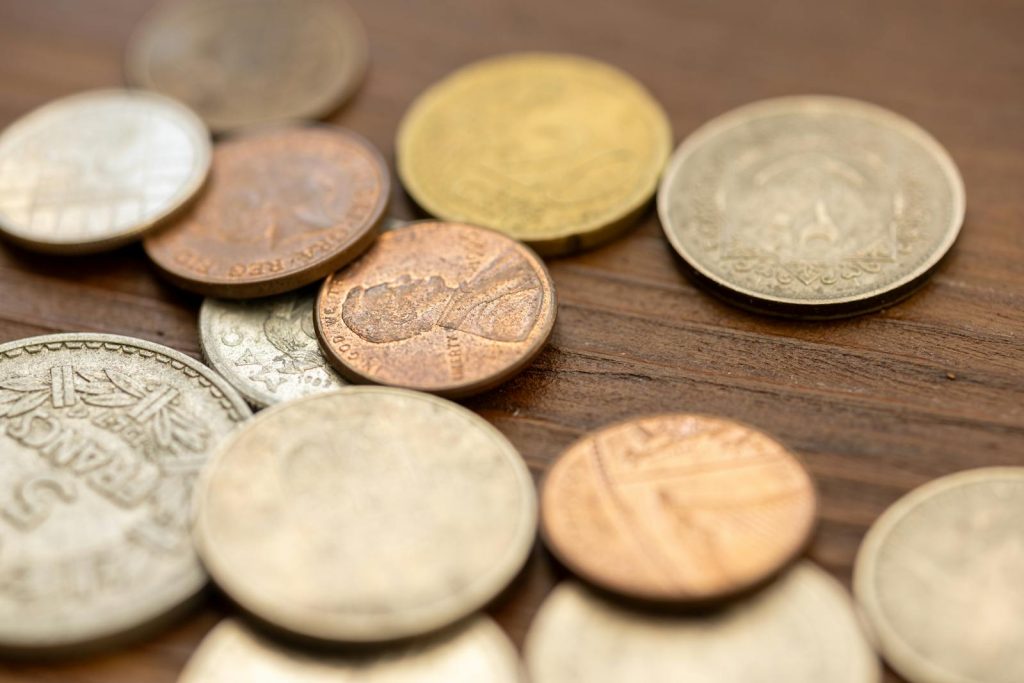 A detailed close-up image showing various vintage coins scattered on a wooden surface, capturing their unique textures and engravings.