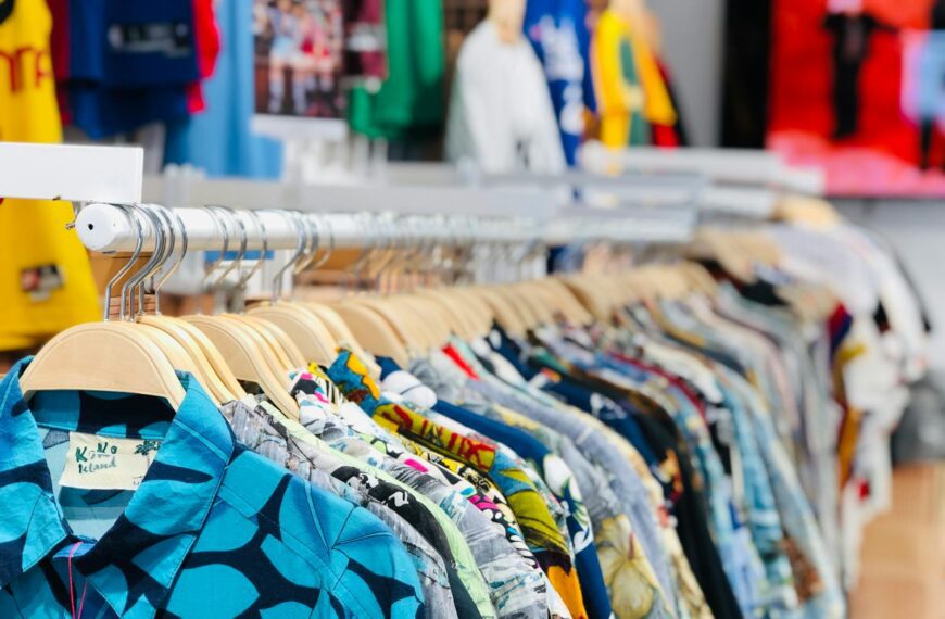 A vibrant collection of Hawaiian shirts on hangers in a clothing store with varied designs and colors.