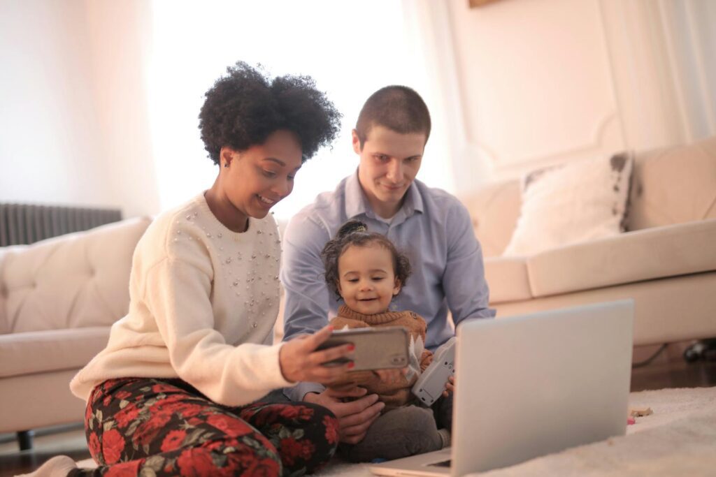 A joyful family spending time together with technology, capturing happy moments indoors.