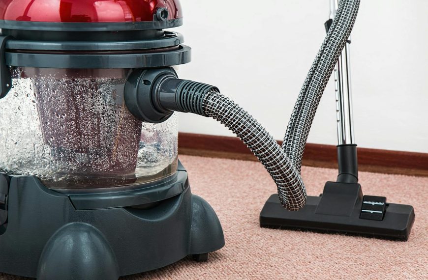Close-up of a modern vacuum cleaner with water filtration on carpet floor indoors.