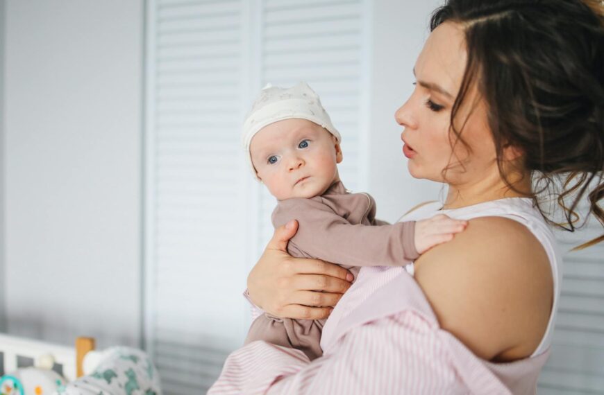 A loving mother holding her baby indoors, illustrating warmth and family bonding.