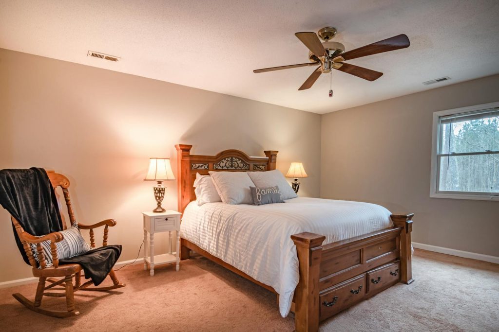 Warm and inviting bedroom featuring a wooden bed, ceiling fan, and cozy decor.