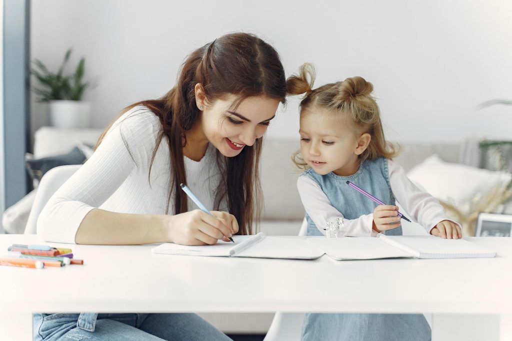 A mother and daughter enjoy a bonding moment while doing homework together indoors.