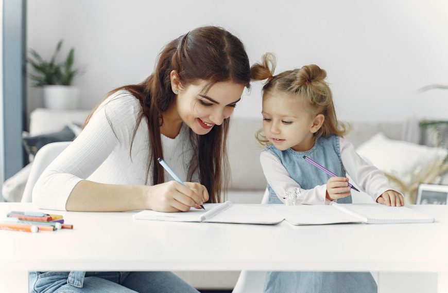 A mother and daughter enjoy a bonding moment while doing homework together indoors.