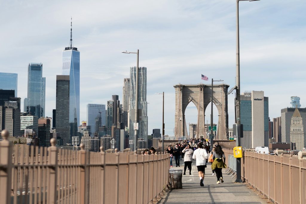 People running on brooklyn bridge with new york city skyline.