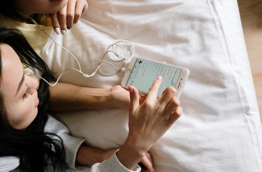 Two young women sharing music on a smartphone while relaxing indoors.