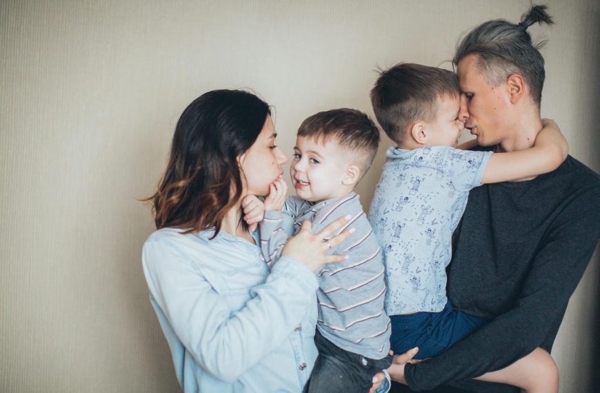 A loving family of four sharing moments of affection indoors.