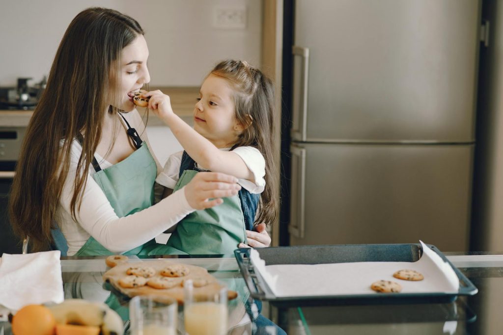A joyful moment of a mother and daughter baking cookies together in the kitchen.