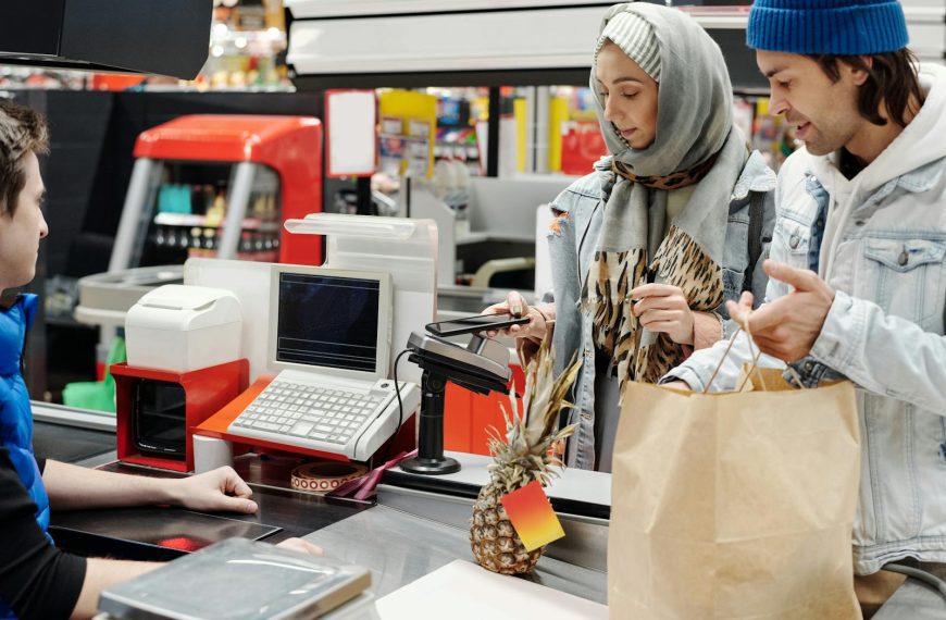 A couple in a supermarket checkout using mobile payment with a cashier. Modern retail technology.
