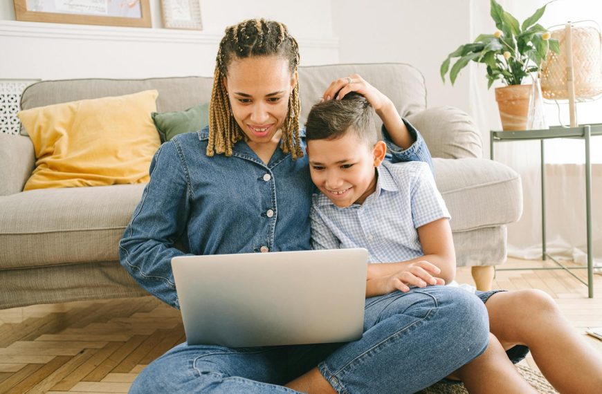 A loving mother and her son enjoying a fun time together while using a laptop indoors.