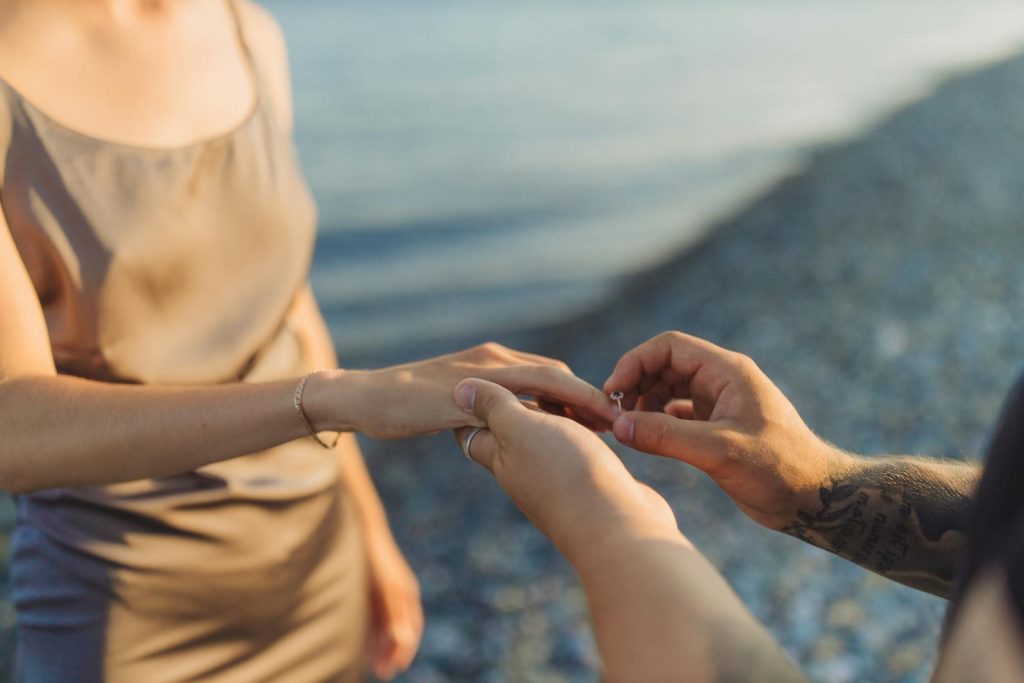 A couple getting engaged by the sea, capturing a romantic moment at sunset.