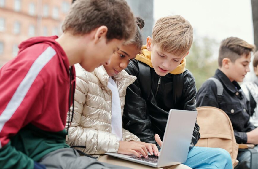 Group of teenagers studying together on a laptop outdoors, fostering collaboration.