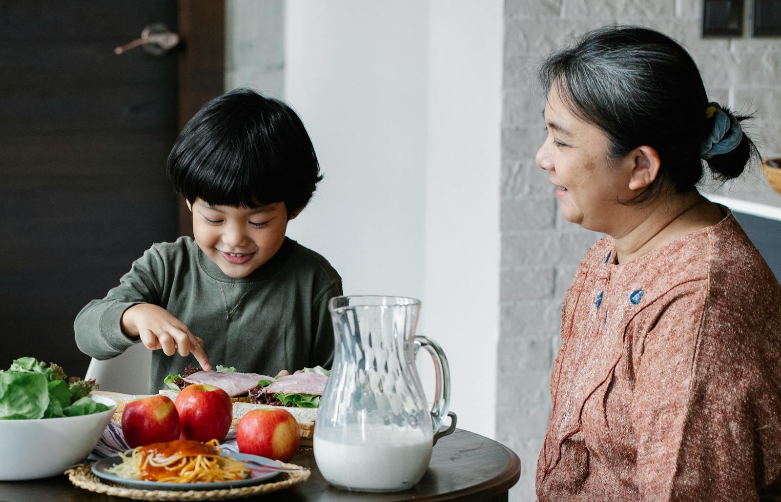 A joyful moment shared between a grandmother and grandson over a homemade meal in the dining room.