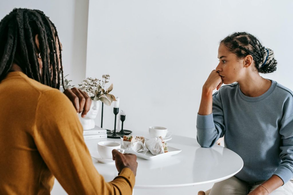 Young African American man sitting with woman at table and having conflict with each other at home