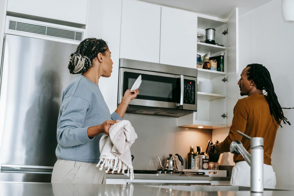 A young couple engaged in a tense conversation in a modern kitchen setting. Emotion and conflict evident.