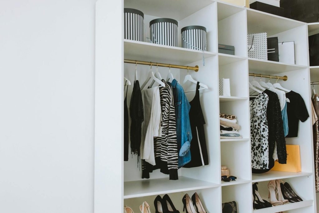 Neatly arranged wardrobe showcasing stylish clothes and shoes indoors.