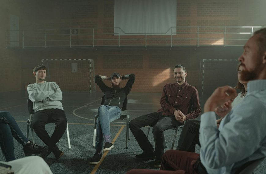 A group of adults engaging in a therapy session in a spacious gymnasium setting.