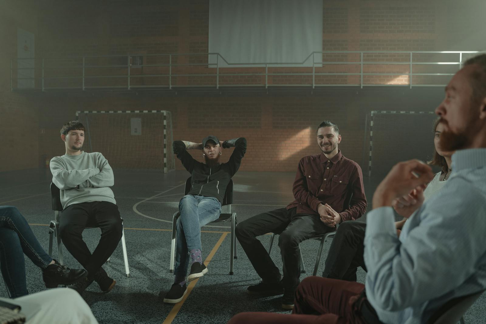 A group of adults engaging in a therapy session in a spacious gymnasium setting.
