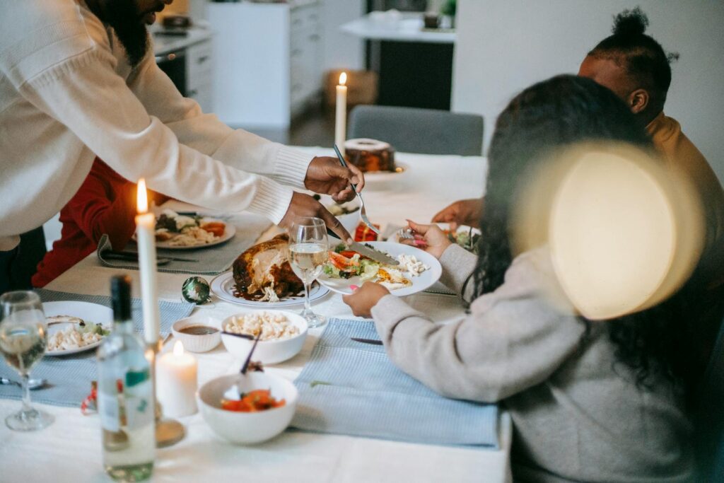 A warm family gathering around a candlelit dinner table, sharing a festive meal.