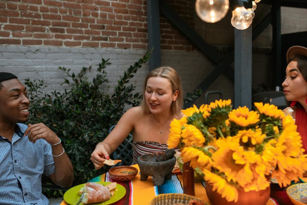 A group of diverse friends enjoying Mexican cuisine and vibrant sunflowers outdoors.