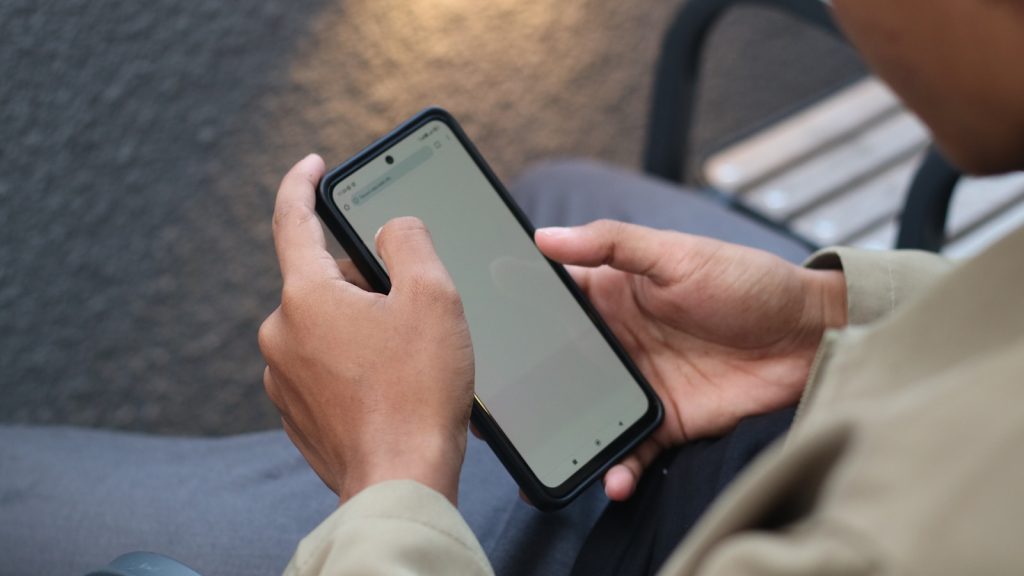 A person sitting on a bench using a cell phone