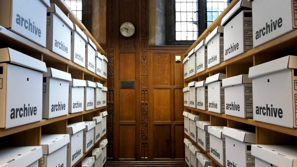 Rows of white archive boxes on wooden shelves