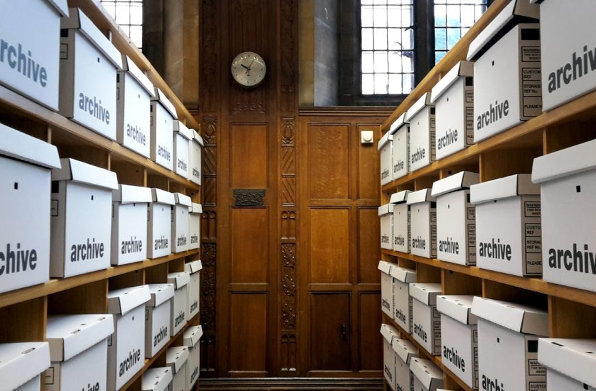 Rows of white archive boxes on wooden shelves