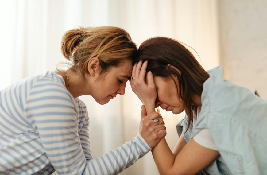 Two women comfort each other in a moment of emotional support indoors.