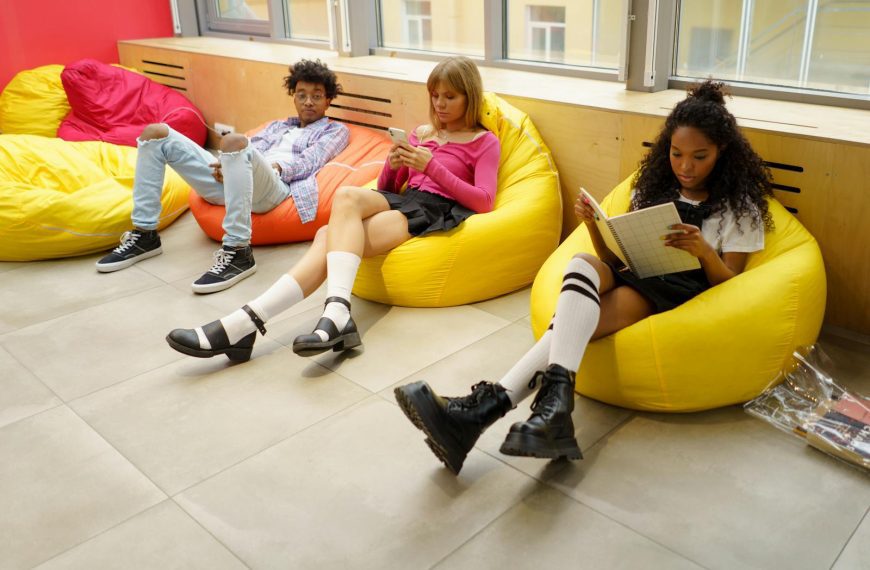 Group of students relaxing and studying on colorful bean bags in a university lounge.