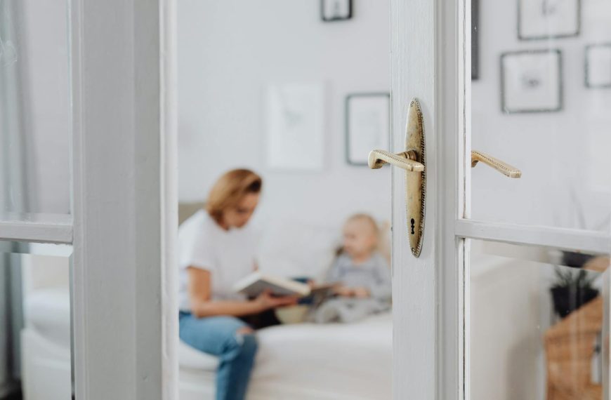 A mother lovingly reads to her daughter in a bright and cozy bedroom setting.