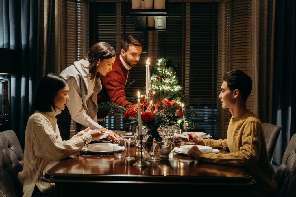 A cozy festive dinner setting with friends celebrating together around a candlelit table.