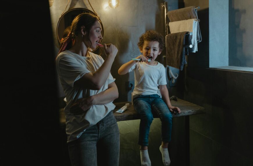 A mother and son brush their teeth together in a warmly lit bathroom, promoting good hygiene habits.