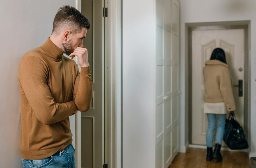 A couple experiencing a tense moment as a woman walks out of the apartment.