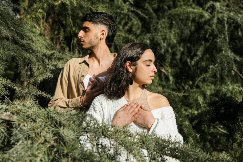 A young couple meditates amidst lush greenery, exuding relaxation and inner peace.